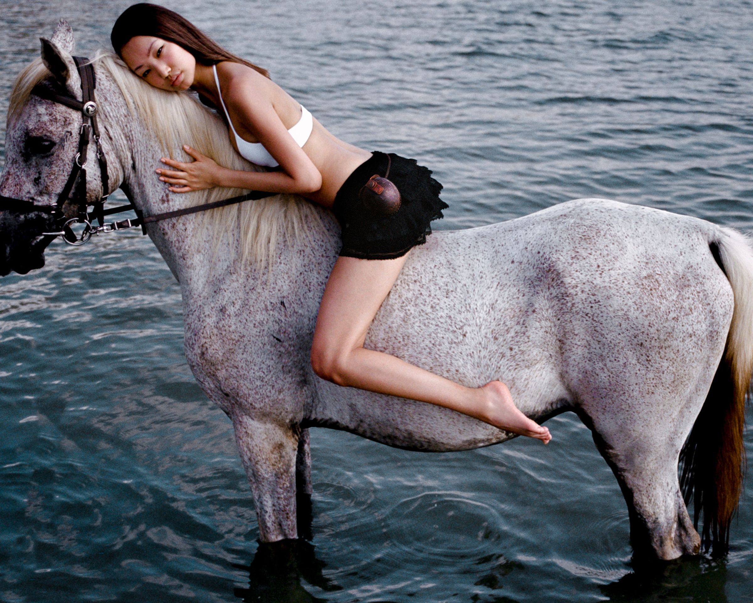 Tank Air SS24 ready-to-wear shot in Bangkok by Erika Kamano. Model wearing the Jellyfish Mini Skirt in Black lying on horse back in water.