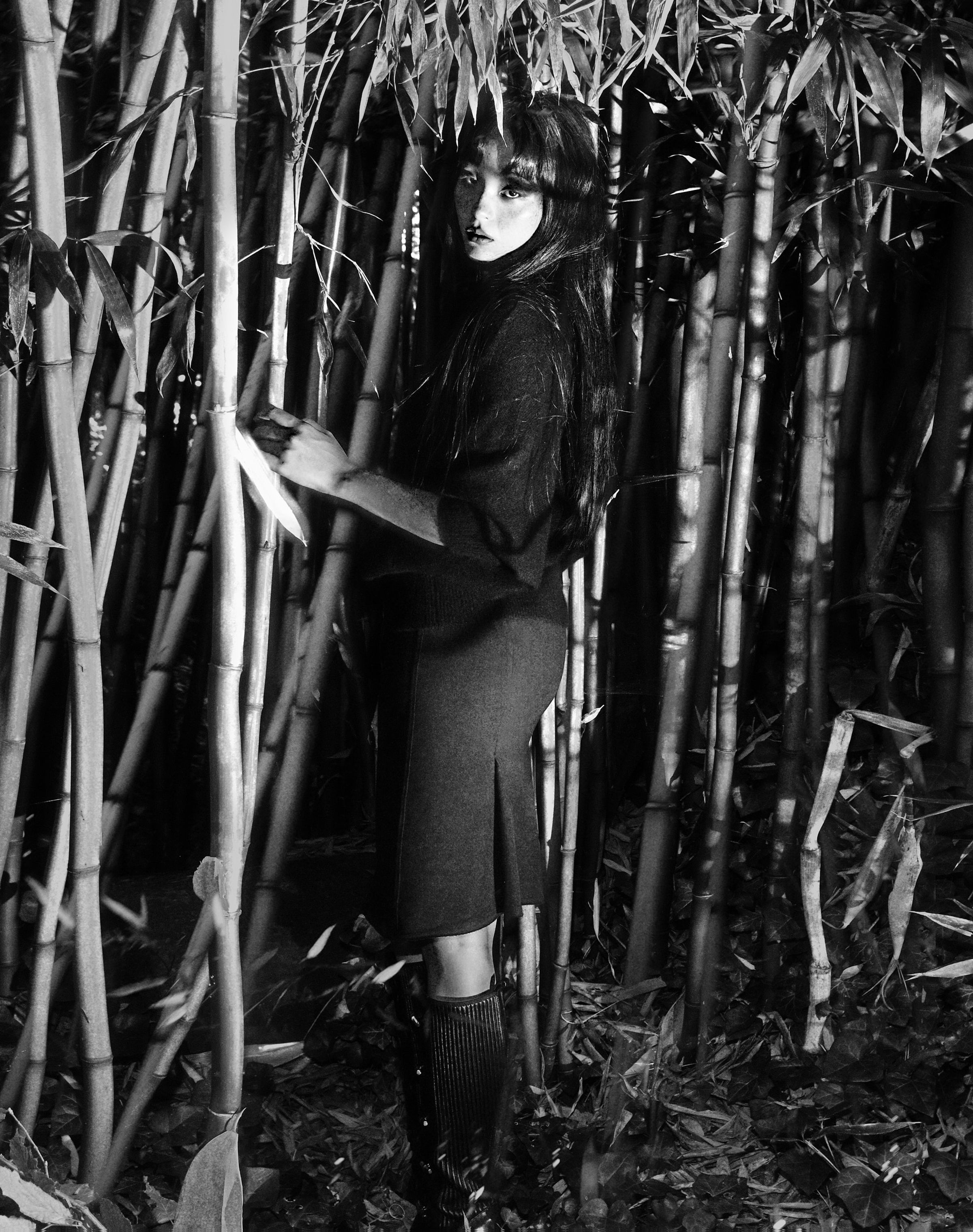 Tank Air FW25 ready-to-wear shot in Paris by Joe Lai. Model wearing the Cup and Pleat Skirt and the Cashmere Angel Sweater while standing among bamboo trees.