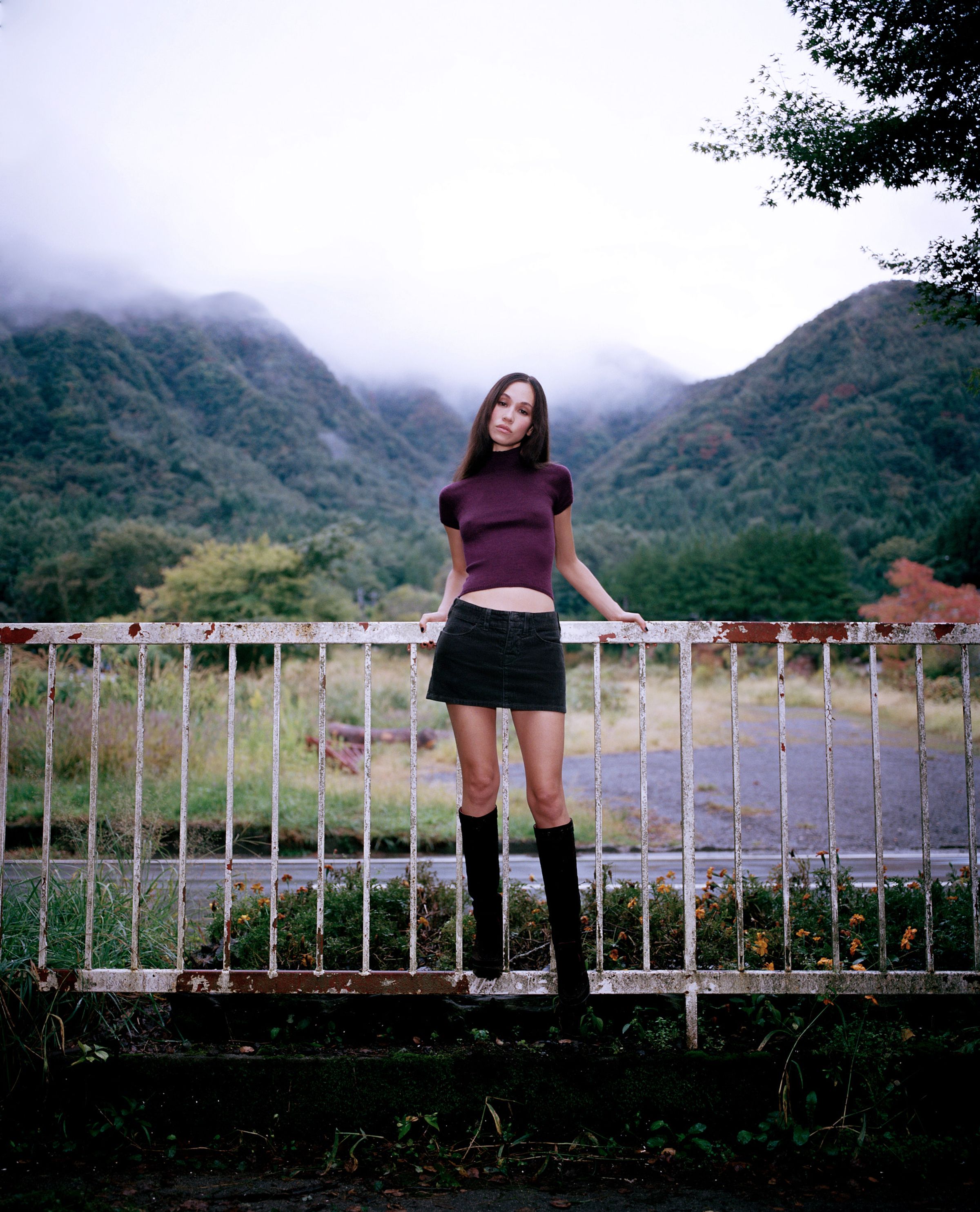 Tank Air FW24 ready-to-wear shot in Tokyo by Erika Kamano. Model wearing Cute Knit Top in Orchid and the Corduroy Mini Skirt in Dark Grey with a landscape view in the back.