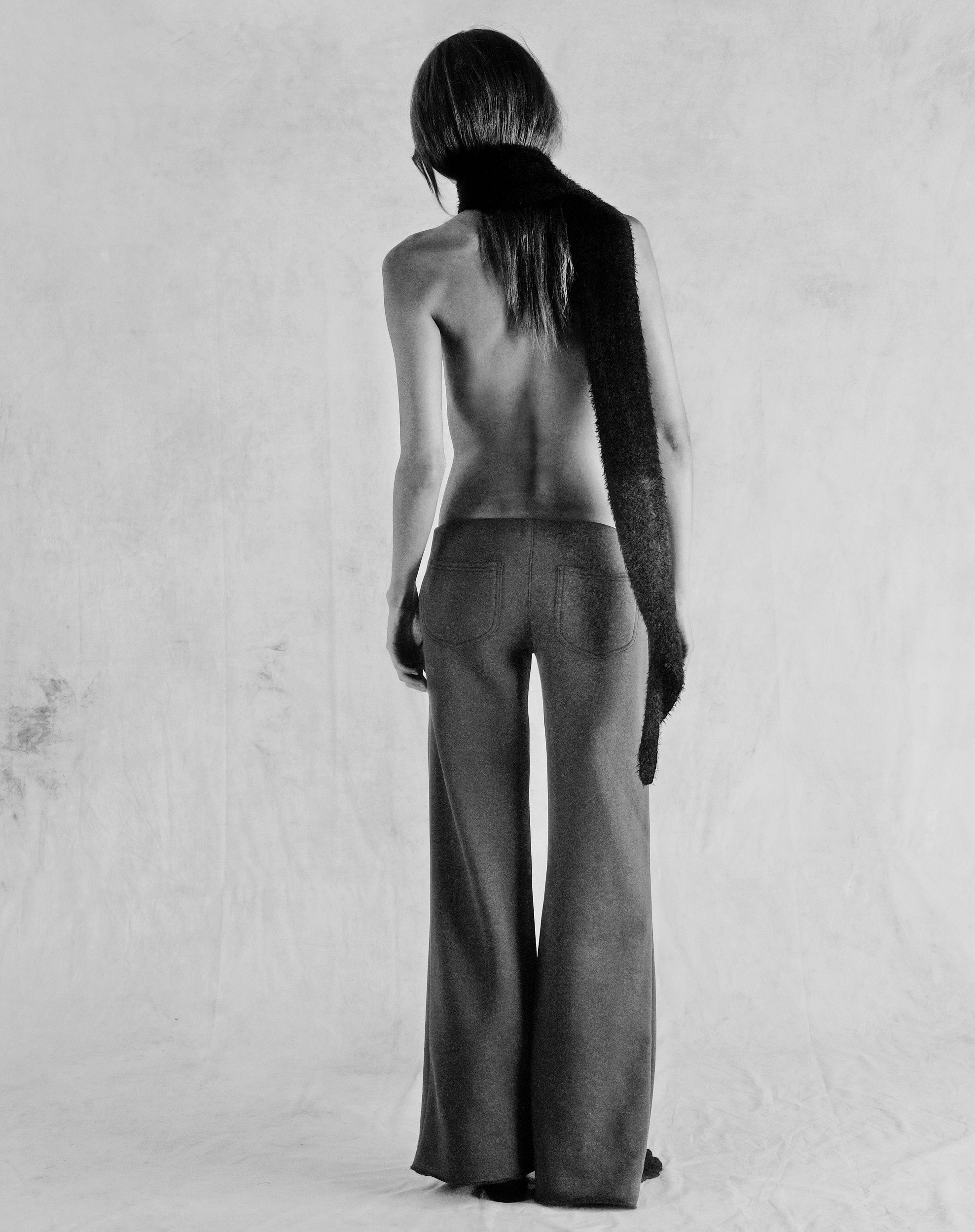 Tank Air FW25 ready-to-wear shot in Paris by Joe Lai. Model wearing the Fluffies Scarf in Black and the Ceremony Sweats while standing away from the camera.