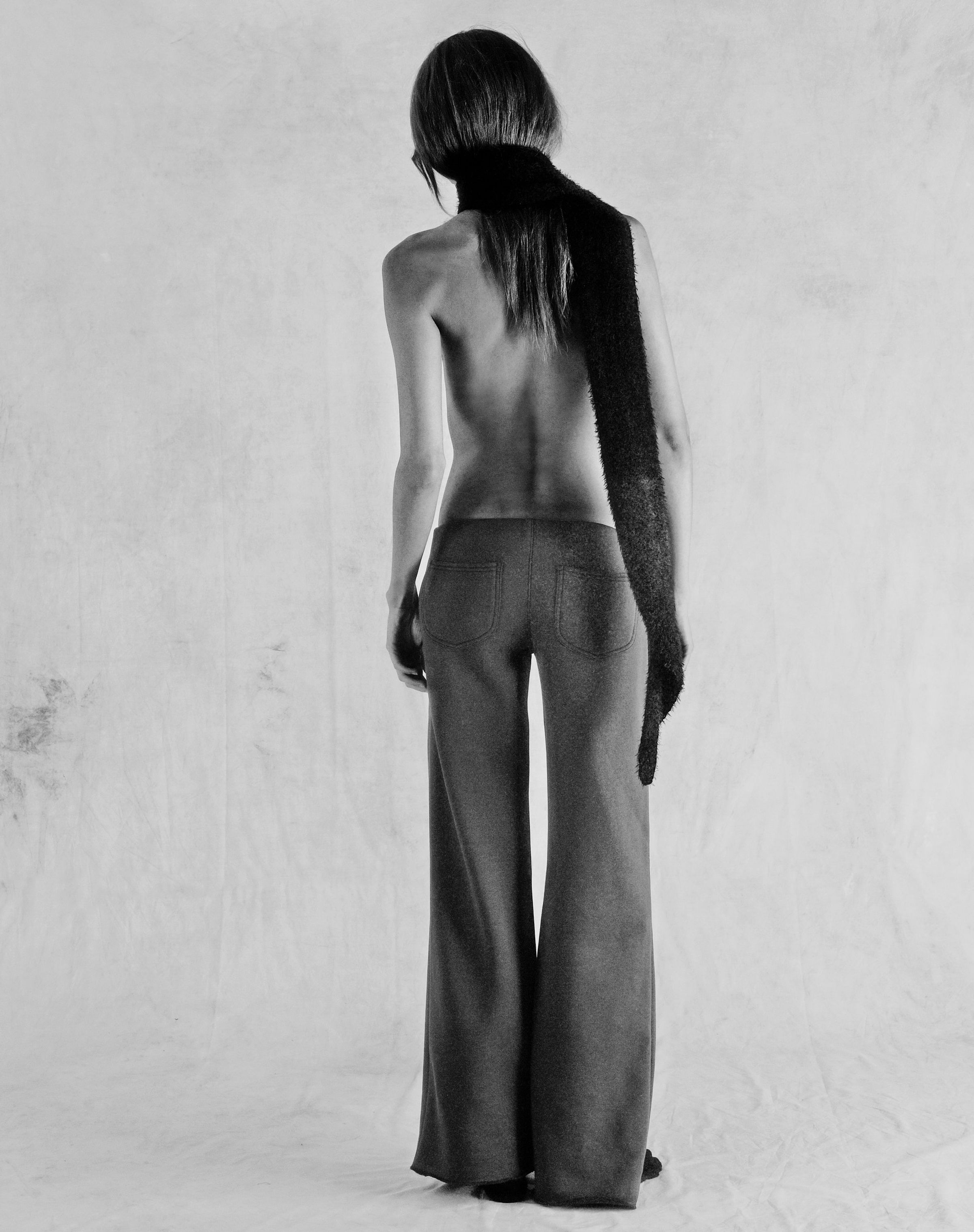 Tank Air FW25 ready-to-wear shot in Paris by Joe Lai. Model wearing the Fluffies Scarf in Black and the Ceremony Sweats while standing away from the camera.