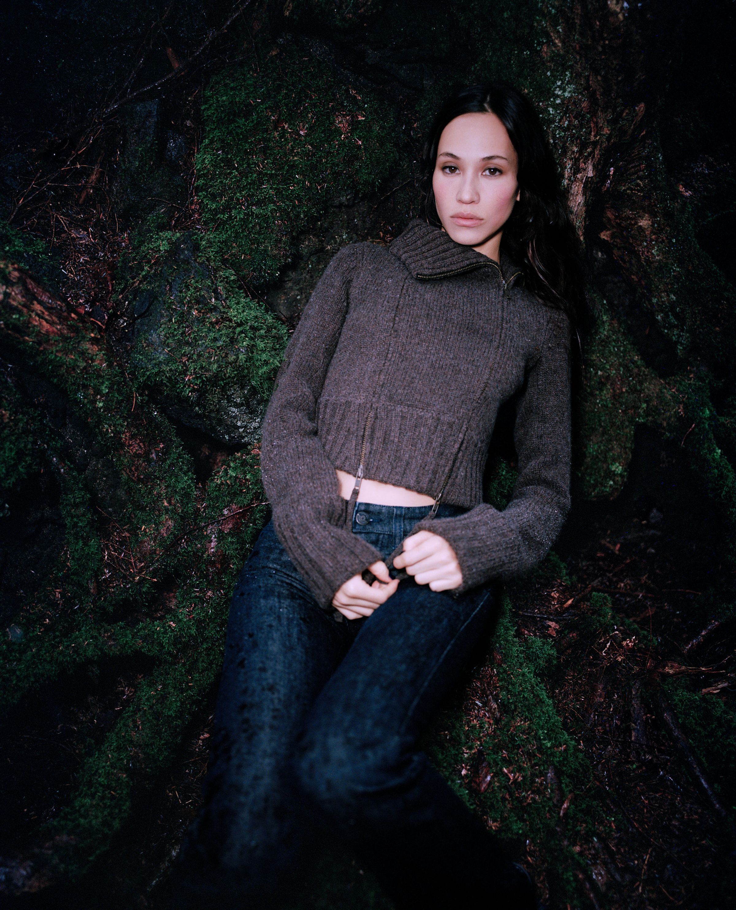 Tank Air FW24 ready-to-wear shot in Tokyo by Erika Kamano. Model wearing the Knit Panel Jacket and Indigo Jeans while lying on mossy roots.