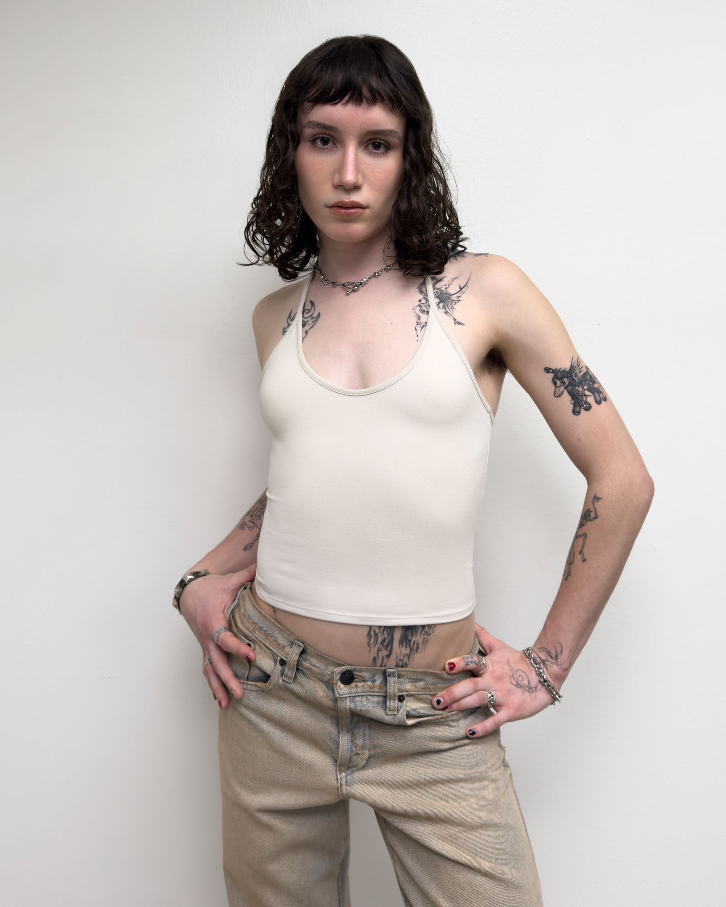 Tank Air SS25 Essentials shot in Los Angeles by Tank Air. Model wearing Half Moon Halter in Soybean against white wall.