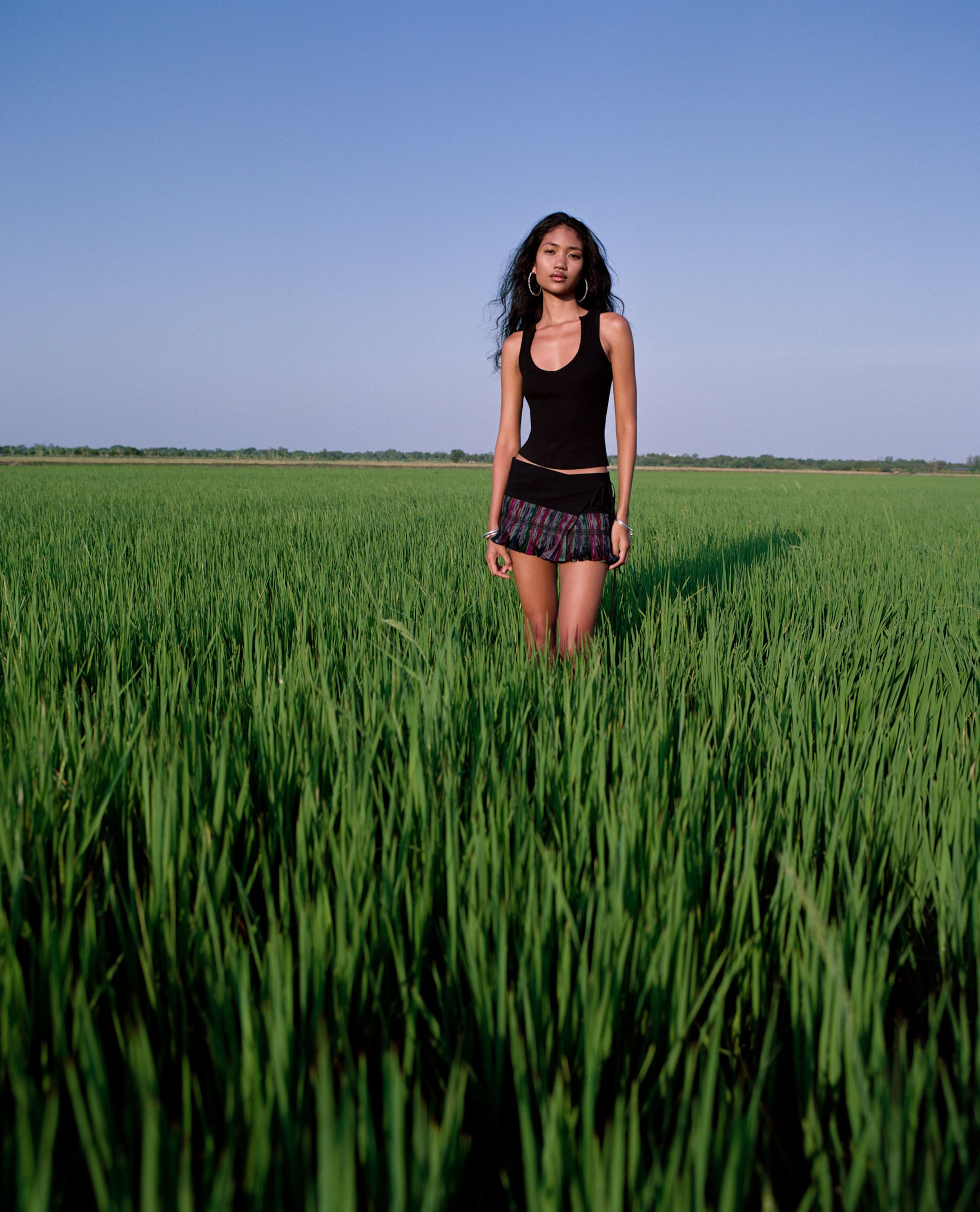 Tank Air SS25 ready-to-wear shot in Bangkok by Erika Kamano & Tank Air. Model wearing the V Tank in Black and the Northern Wrap Mini Skirt while standing in a field of grass.