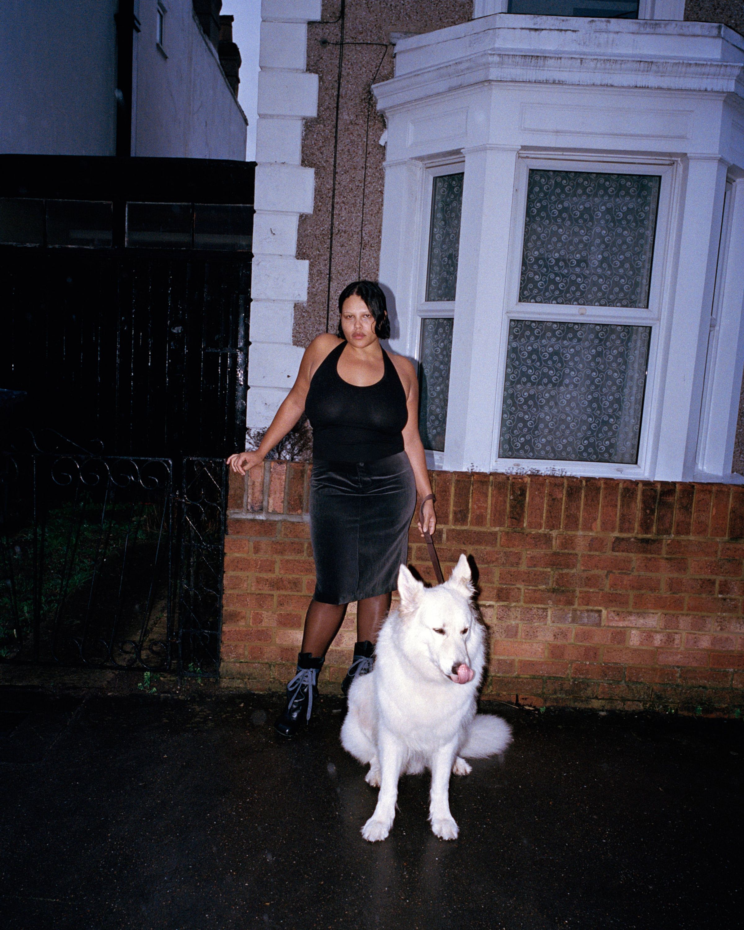 Tank Air SS26 Essentials shot in London by Erika Kamano. Model wearing the Teardrop Halter in Black with white dog standing in front of a home.