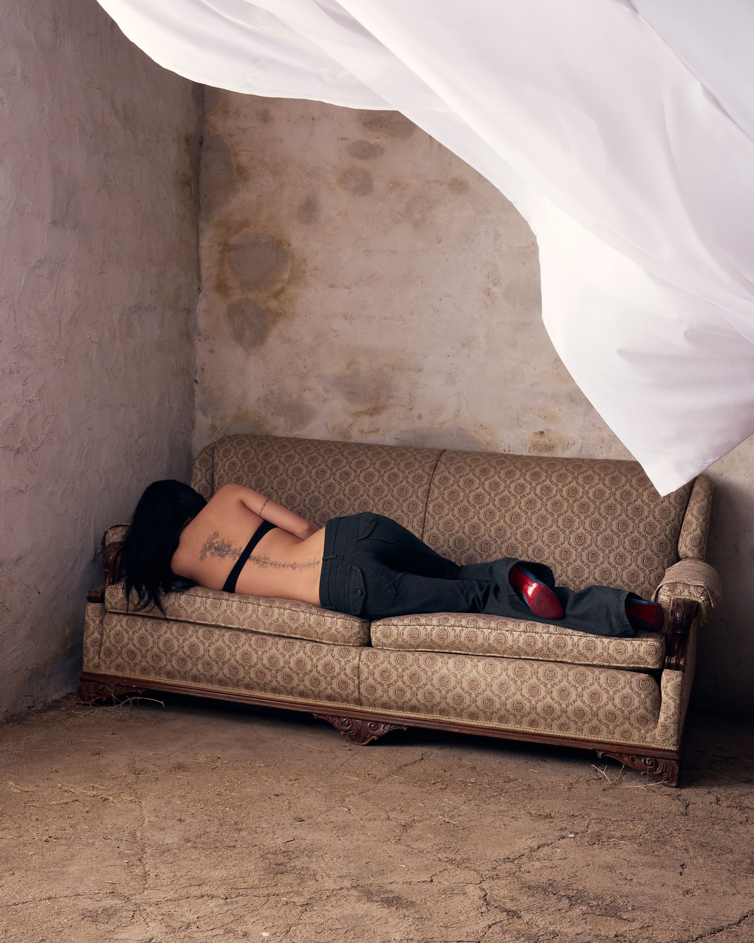 Tank Air SS26 Denim shot in Los Angeles by Tank Air. Model wearing Tulip Bootcut Jeans and Scooped Bralette in Black while lying on couch from back.