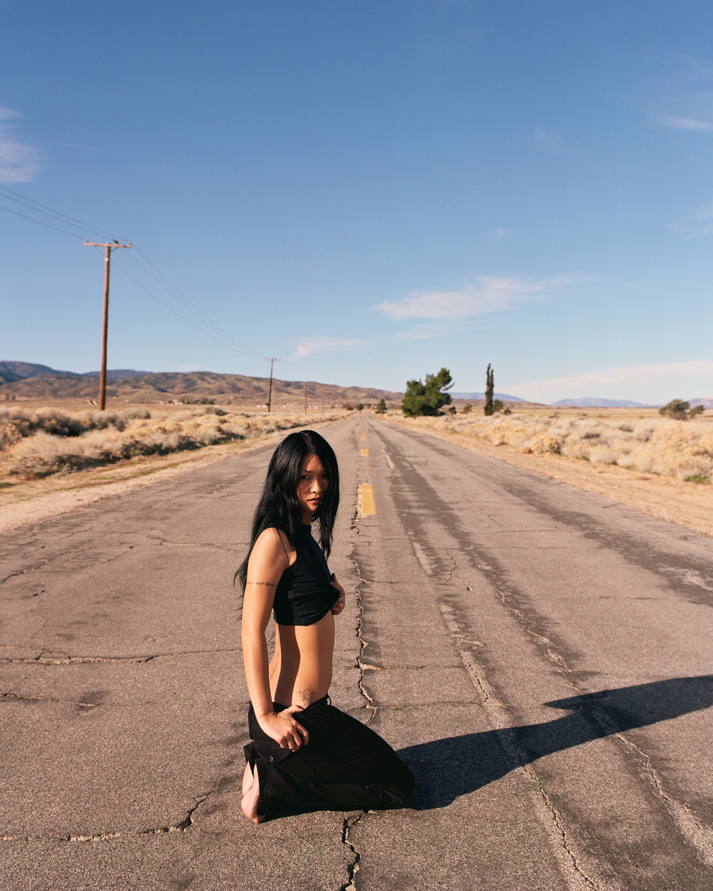 Tank Air SS26 Denim shot in Los Angeles by Tank Air. Model wearing Tulip Relaxed Jeans kneeling in center of a road..