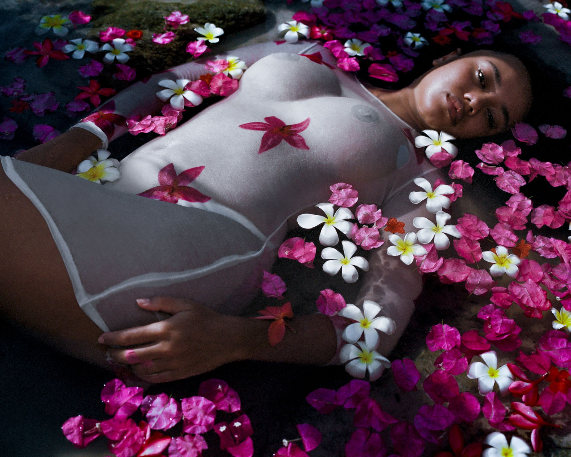 Tank Air SS24 ready-to-wear shot in Bangkok by Erika Kamano. Model wearing the Plumeria Mini Dress lying in water full of flower petals.
