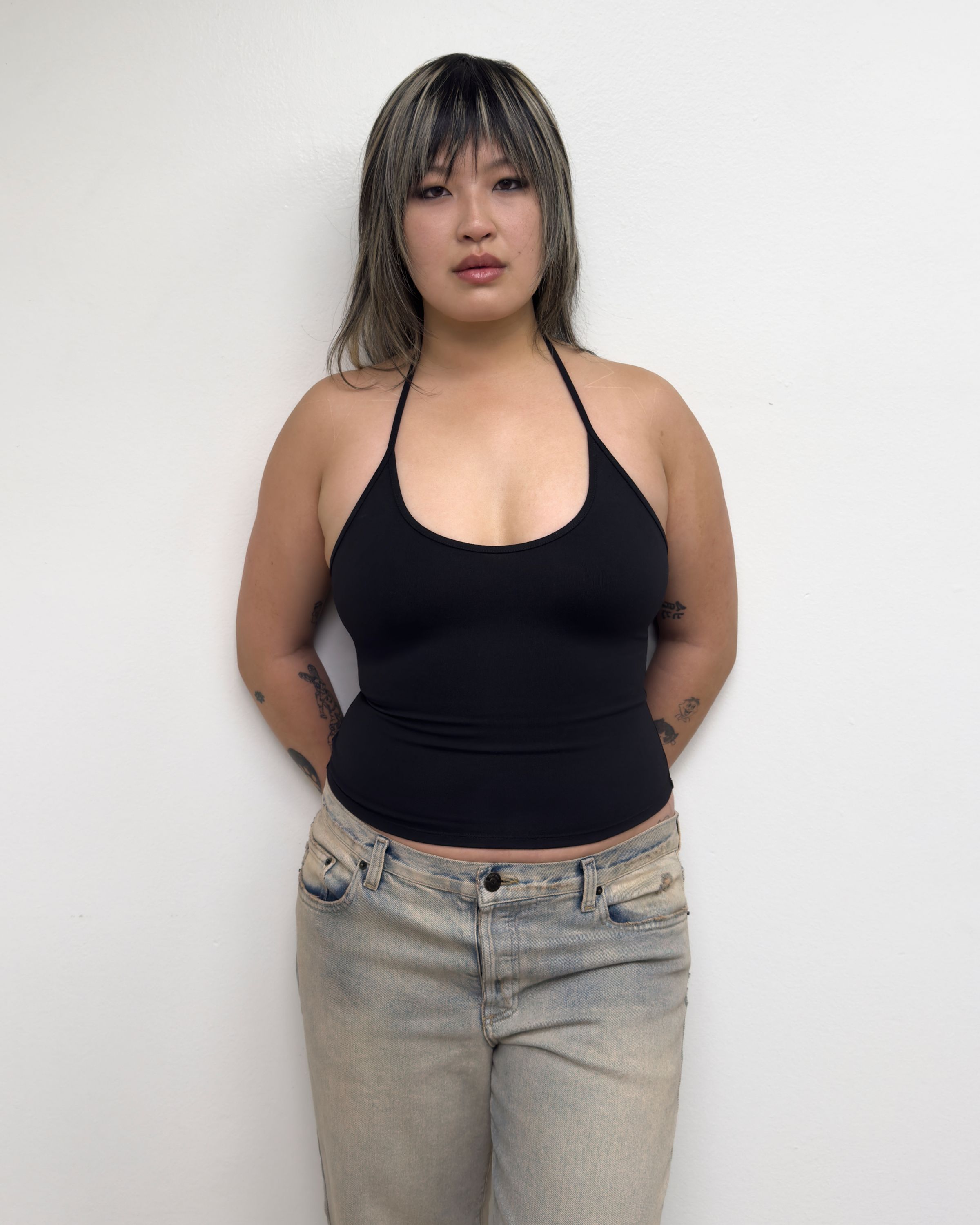 Tank Air SS25 Essentials shot in Los Angeles by Tank Air. Model wearing Half Moon Halter in Black against white wall.