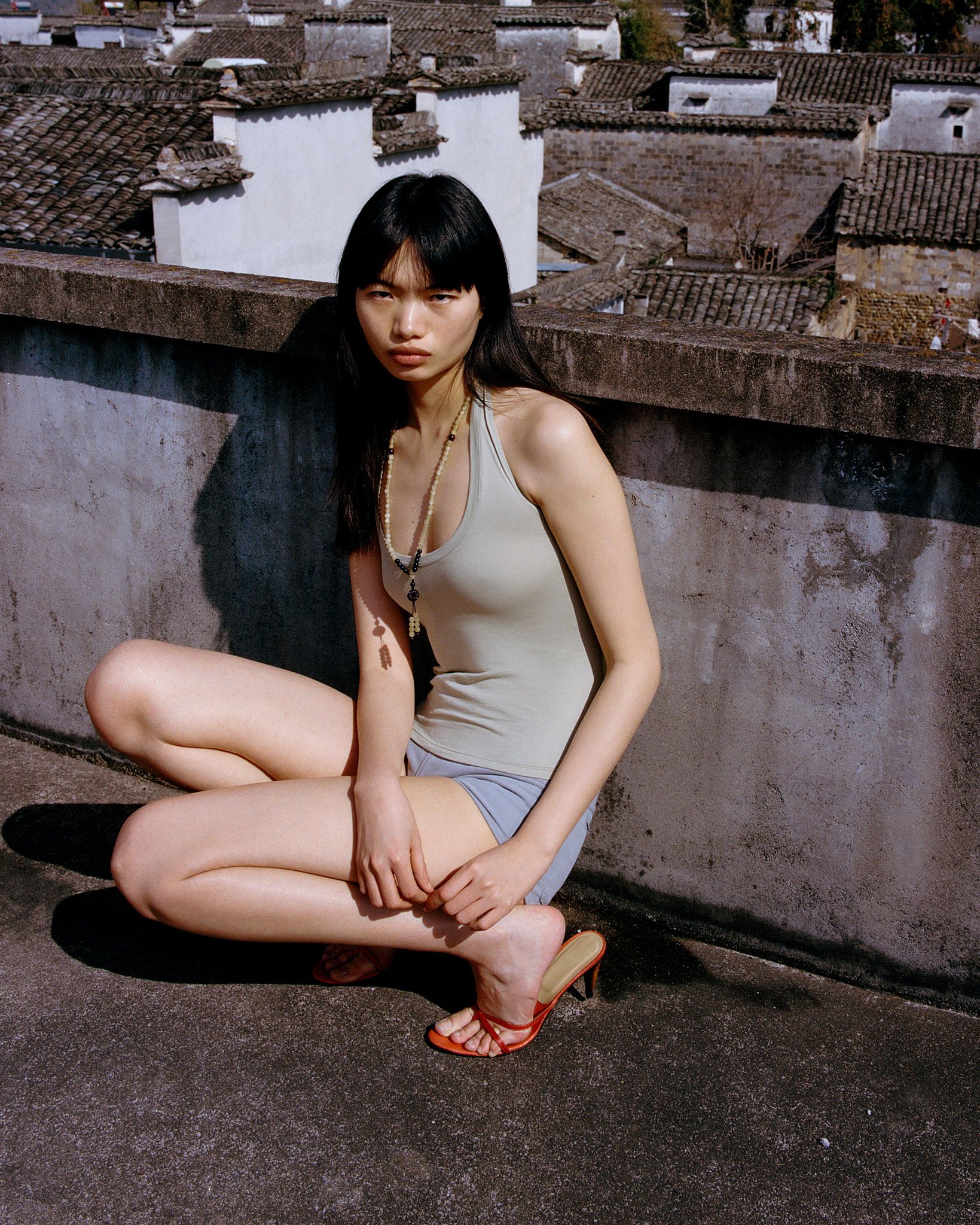 Tank Air SS26 Essentials shot in Nanping Village in Erika Kamano. Model wearing the Teardrop Halter in Celadon and Bliss Hot Pants in Grey while crouching on rooftop.