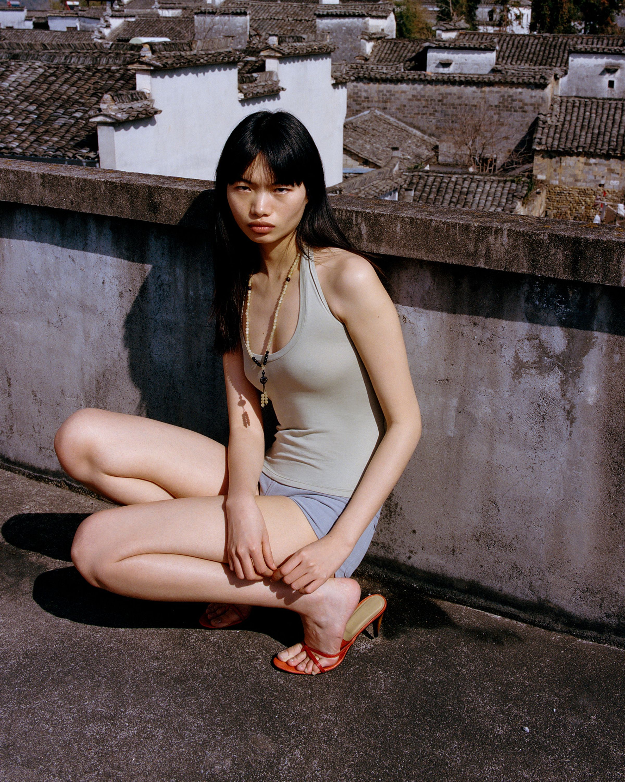 Tank Air SS26 Essentials shot in Nanping Village in Erika Kamano. Model wearing the Teardrop Halter in Celadon and Bliss Hot Pants in Grey while crouching on rooftop.