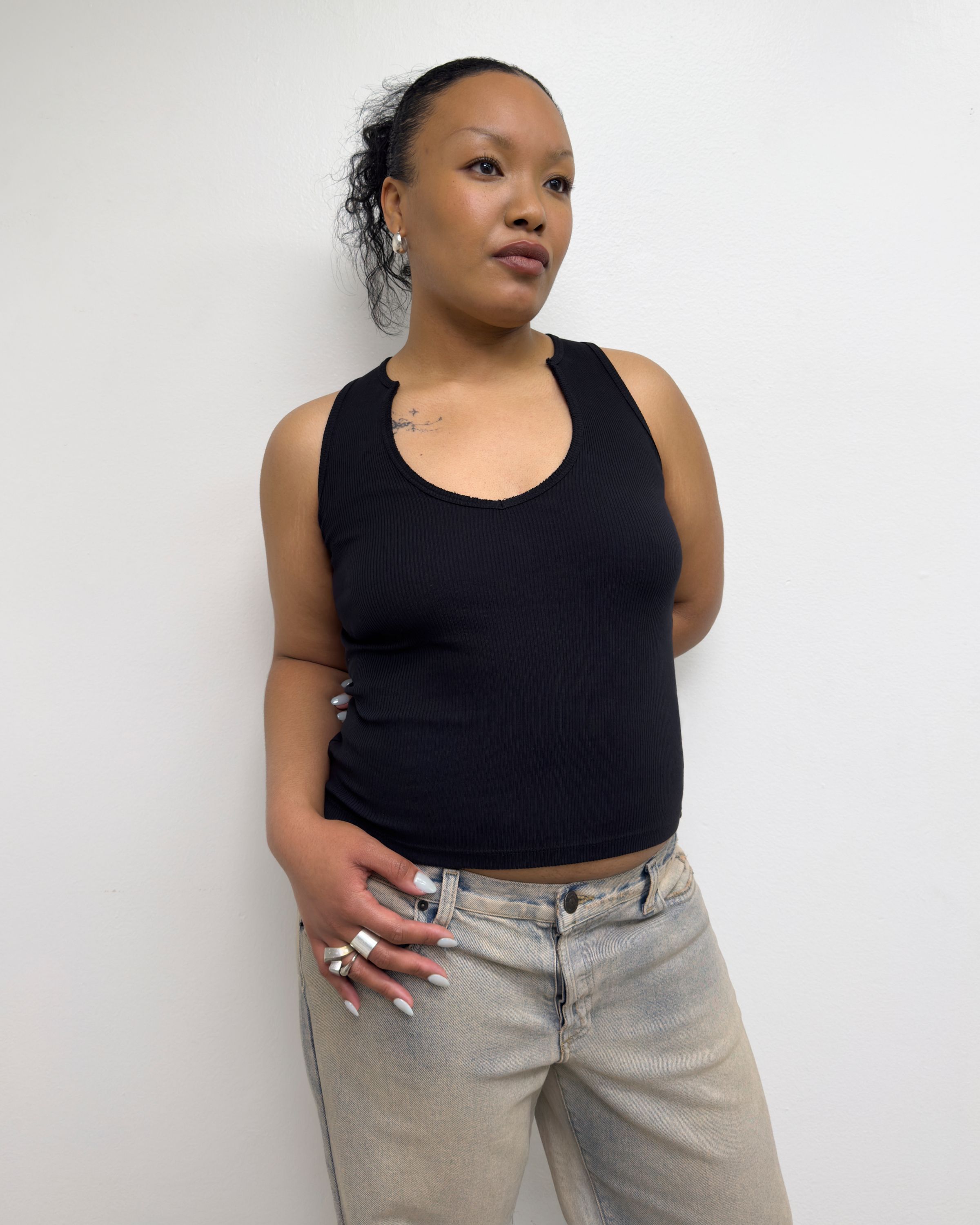 Tank Air SS25 Essentials shot in Los Angeles by Tank Air. Model wearing V Tank in Black against white wall.