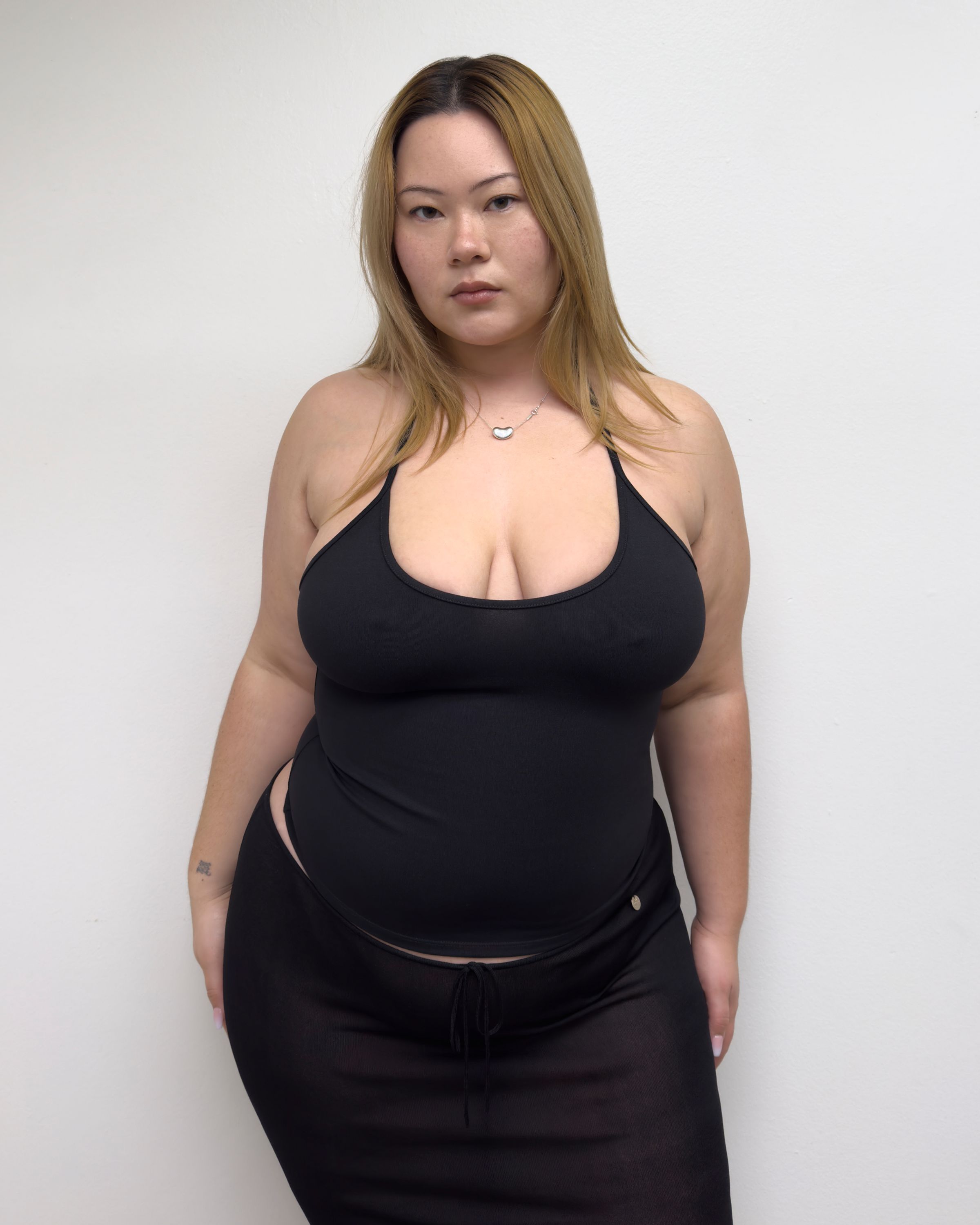 Tank Air SS25 Essentials shot in Los Angeles by Tank Air. Model wearing Half Moon Halter in Black against white wall.
