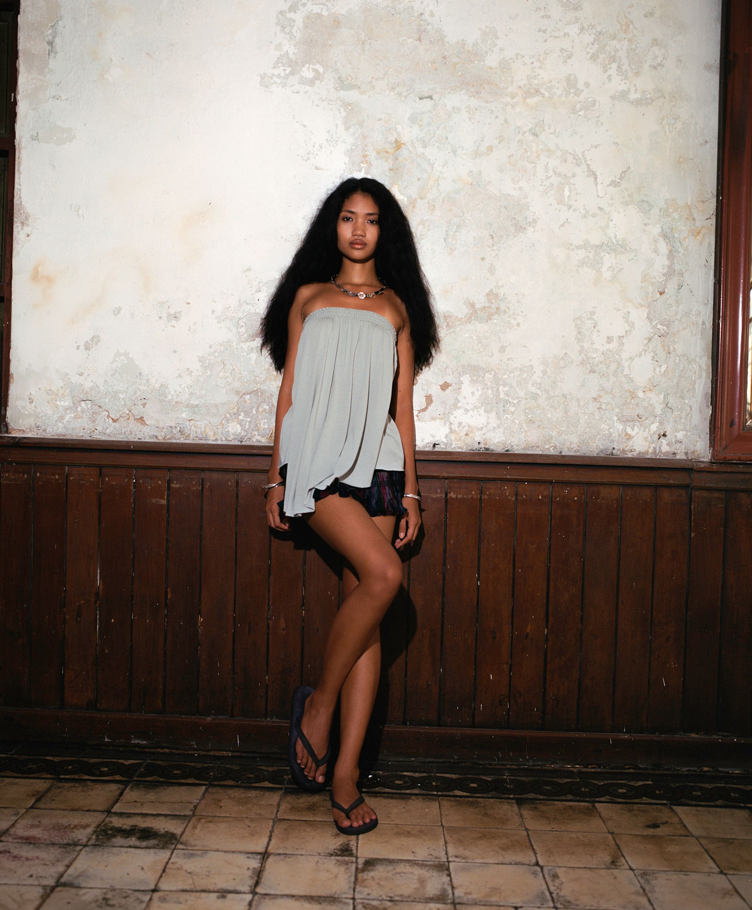 Tank Air SS25 ready-to-wear shot in Bangkok by Erika Kamano & Tank Air. Model wearing the Waterfall Tube Top in Blue Mist and the Northern Wrap Mini Skirt while leaning against a wall.
